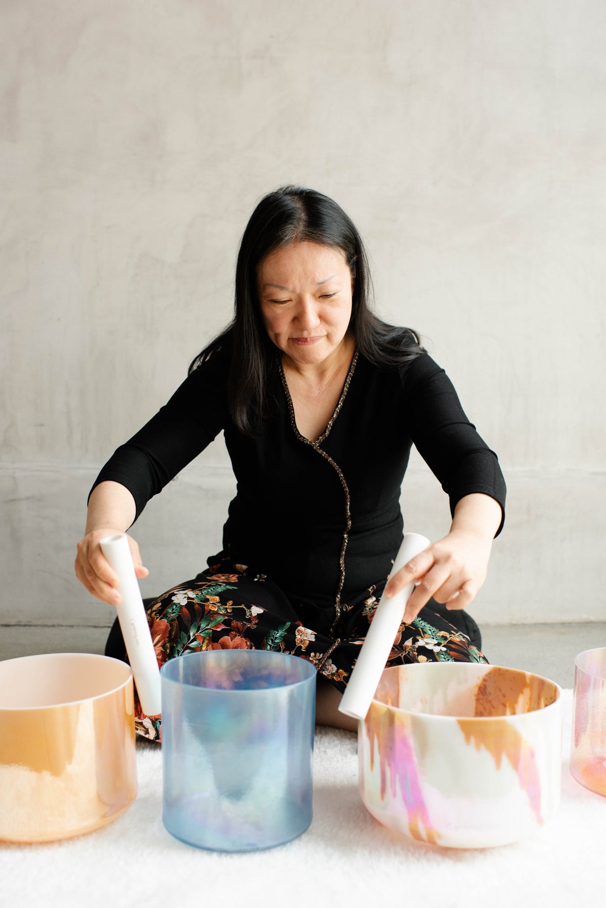 A practitioner playing three crystal singing bowls