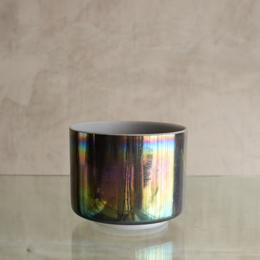 Crystal Tones 7-inch C#+15 crystal singing bowl in Charcoal and Platinum, side view on a glass shelf