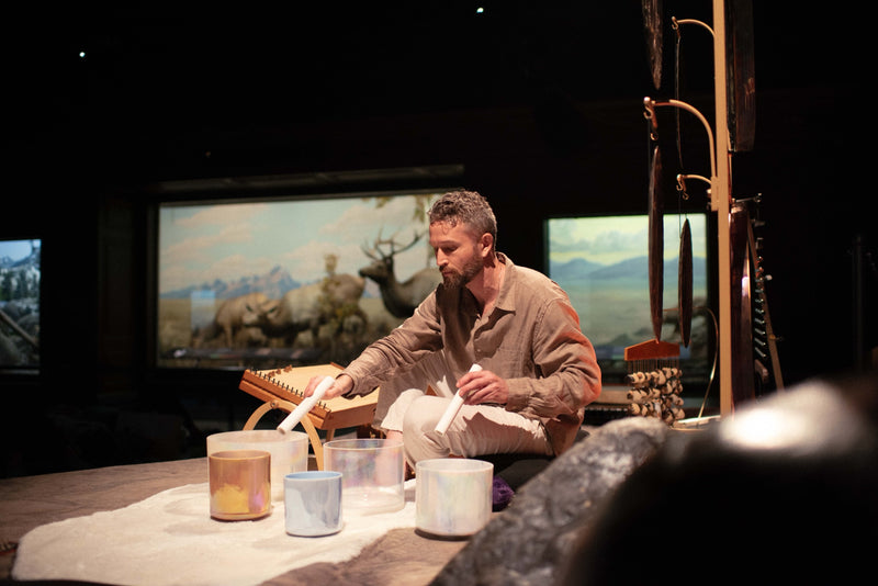 Avery playing crystal singing bowls at a live sound event.