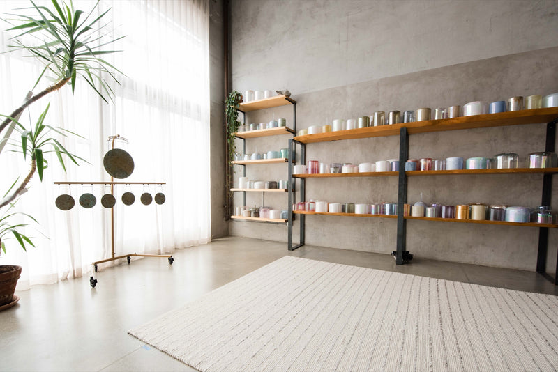 Daylight in the OSO studio, with crystal singing bowls on open shelves and a rack of gongs.